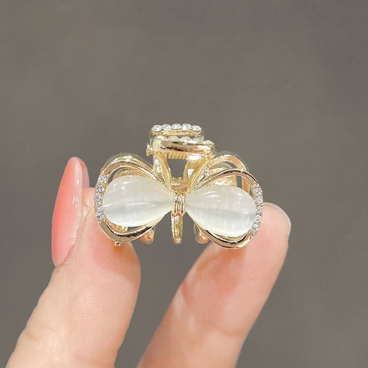 Gold bow mini hair claw clip with a glossy cat-eye inspired finish