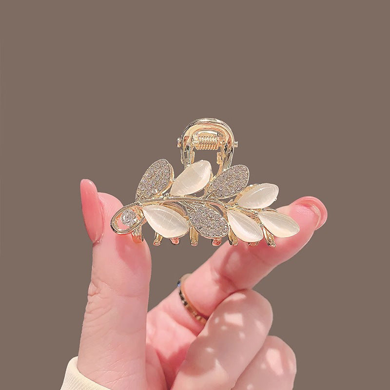 Leaf mini hair claw clip with cat-eye style rhinestone detail shown on a white background